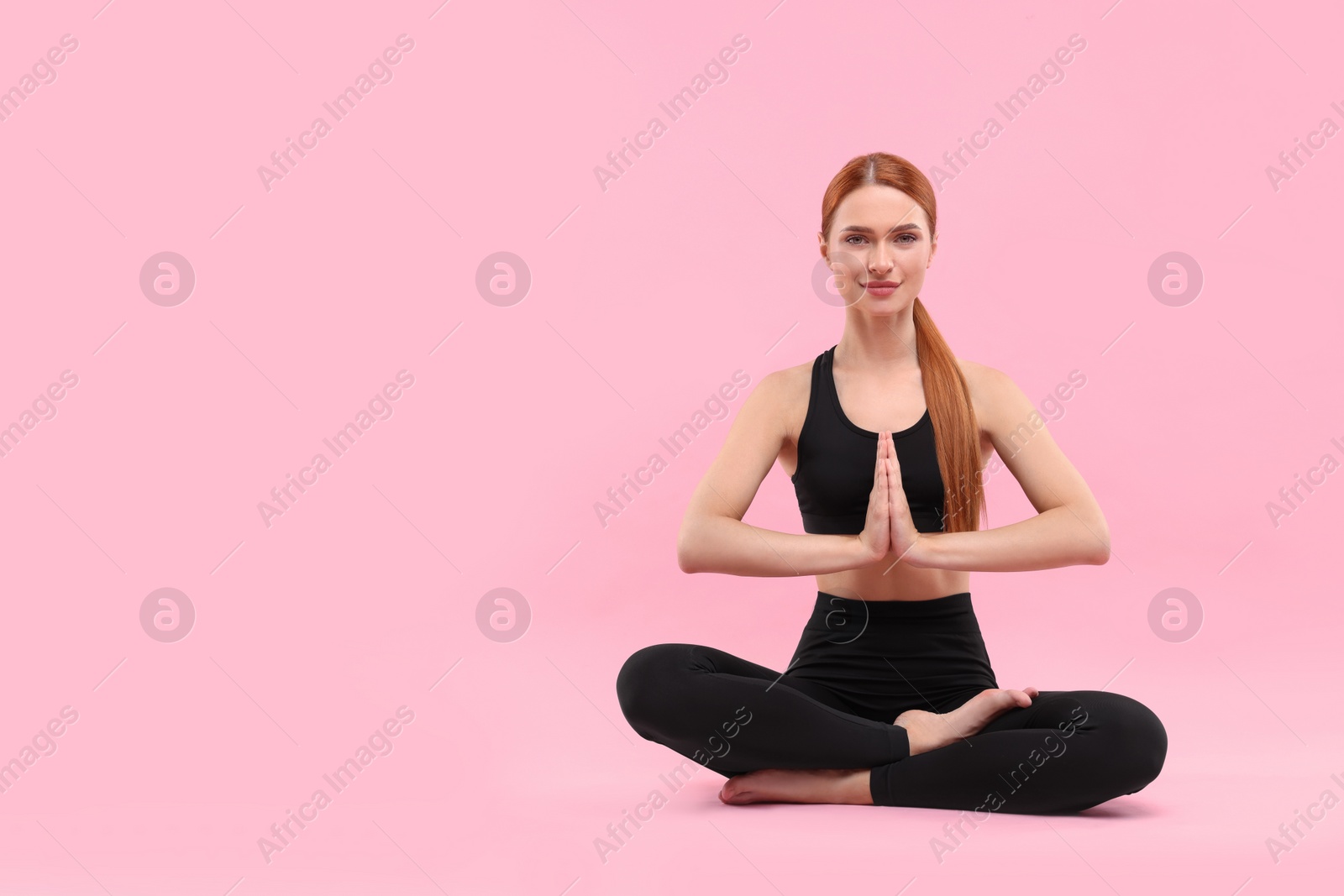 Photo of Beautiful young woman practicing yoga on pink background, space for text. Lotus pose