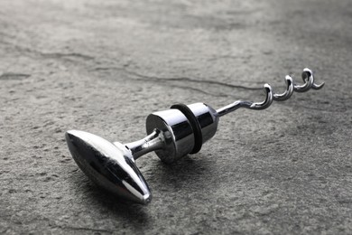 Photo of One metal corkscrew on grey textured table, closeup