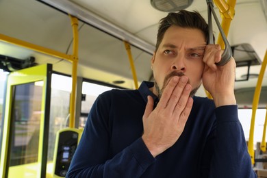 Sleepy tired man yawning in public transport