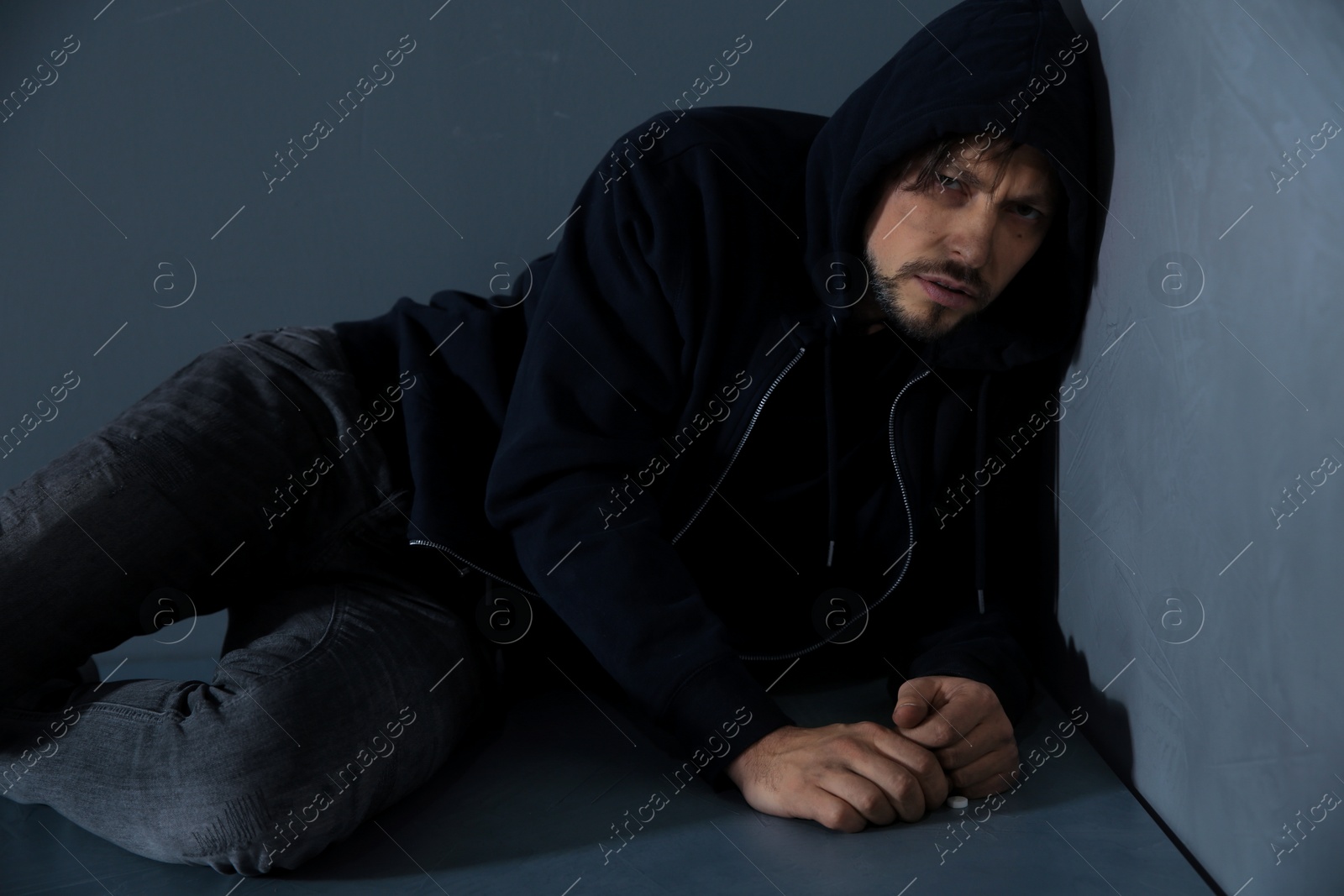 Photo of Passed out junkie after using drugs near grey wall