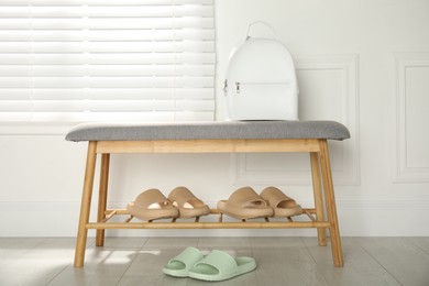 Photo of Stylish rubber slippers and storage bench with shoes in room