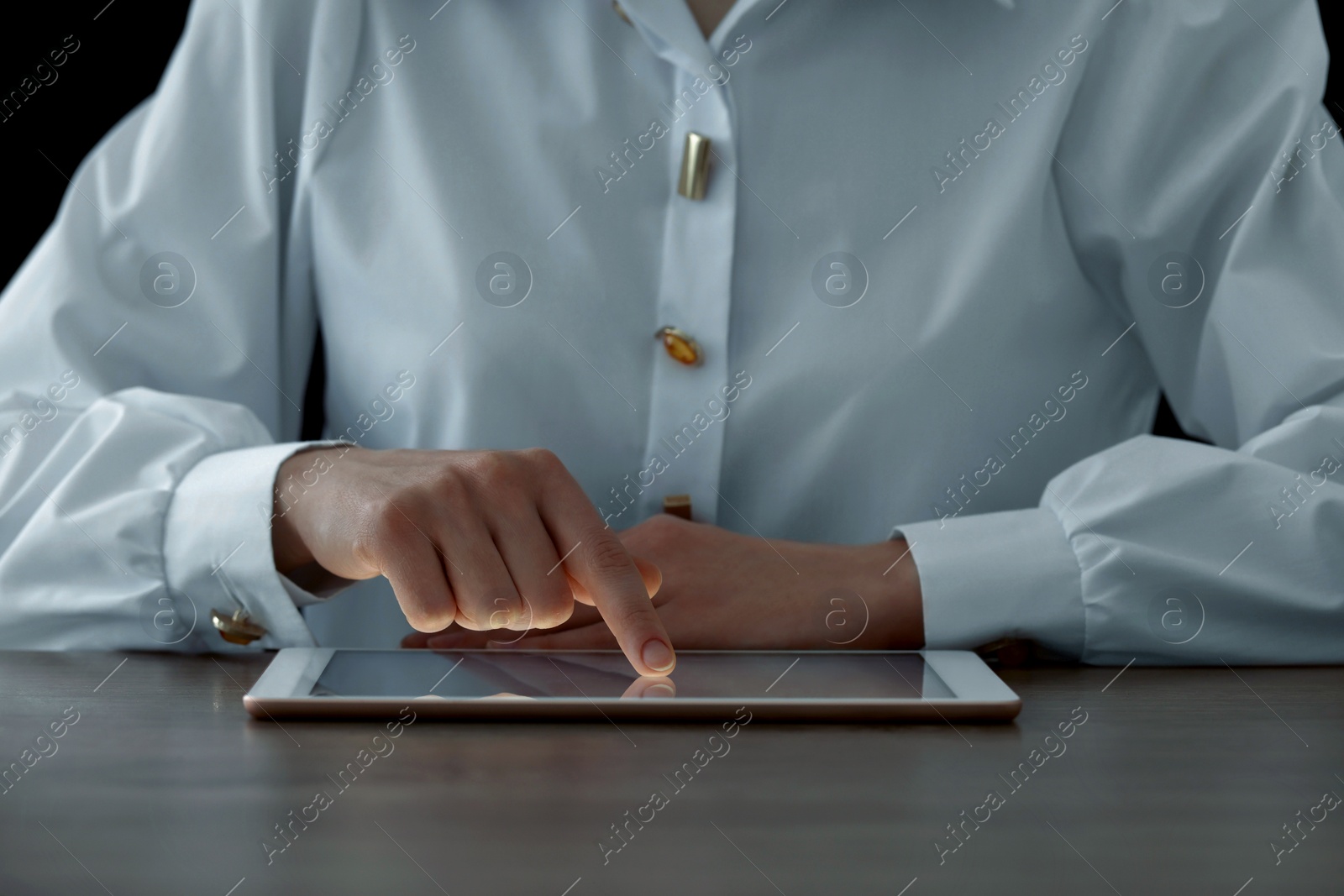 Photo of Closeup view of woman using modern tablet at table on dark background