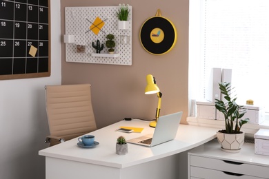 Photo of Stylish workplace interior with laptop on table