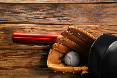 Baseball glove, bat, ball and batting helmet on wooden table, flat lay