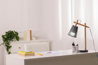 Photo of Stylish teenager's workplace with desk, lamp and stationery