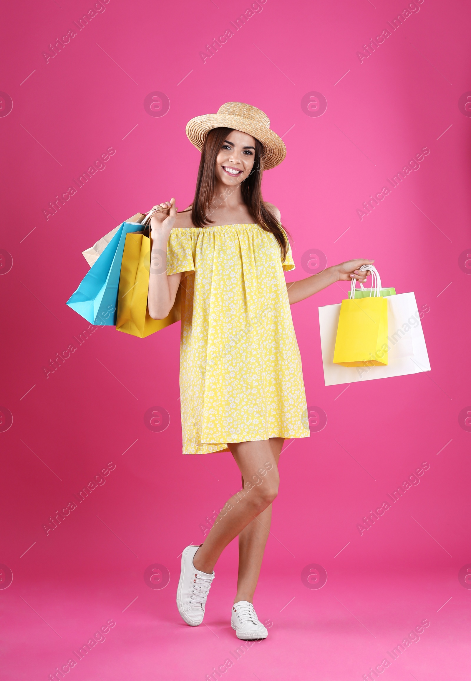 Photo of Young woman with shopping bags on color background