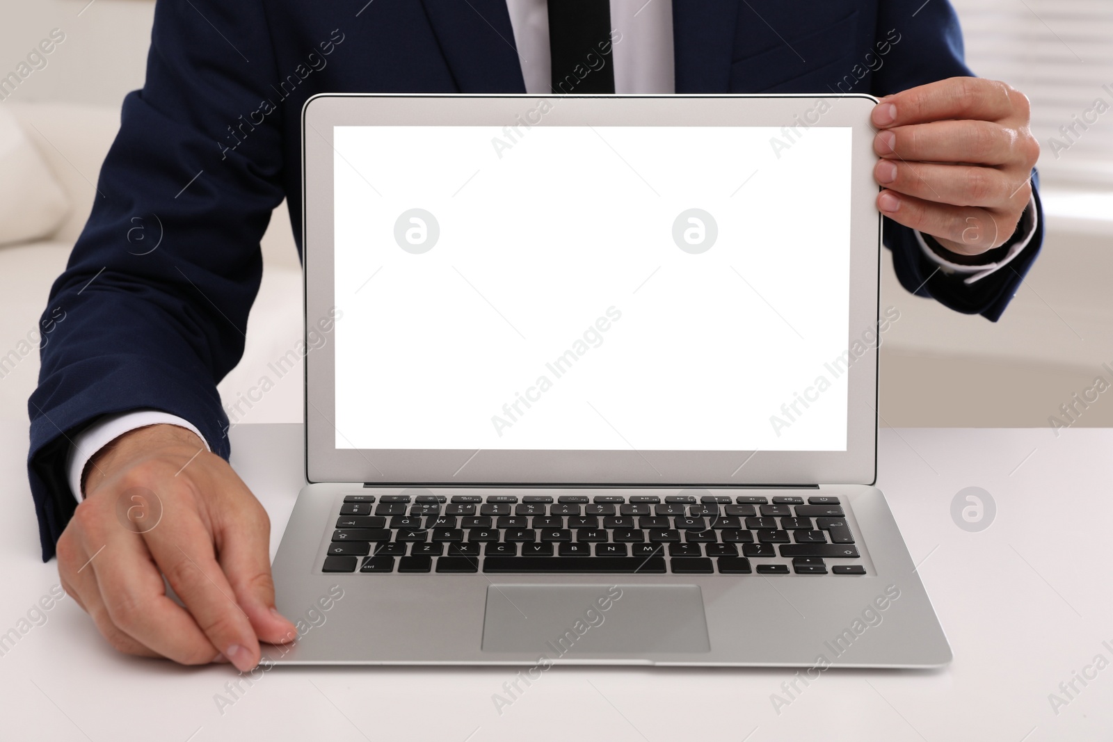 Photo of Businessman with modern laptop at white table indoors, closeup. Space for design