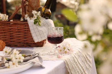 Photo of Stylish table setting with beautiful spring flowers and wine in garden