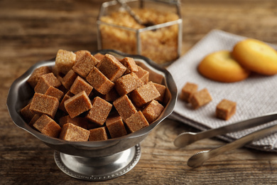 Brown sugar cubes in metal bowl on wooden table