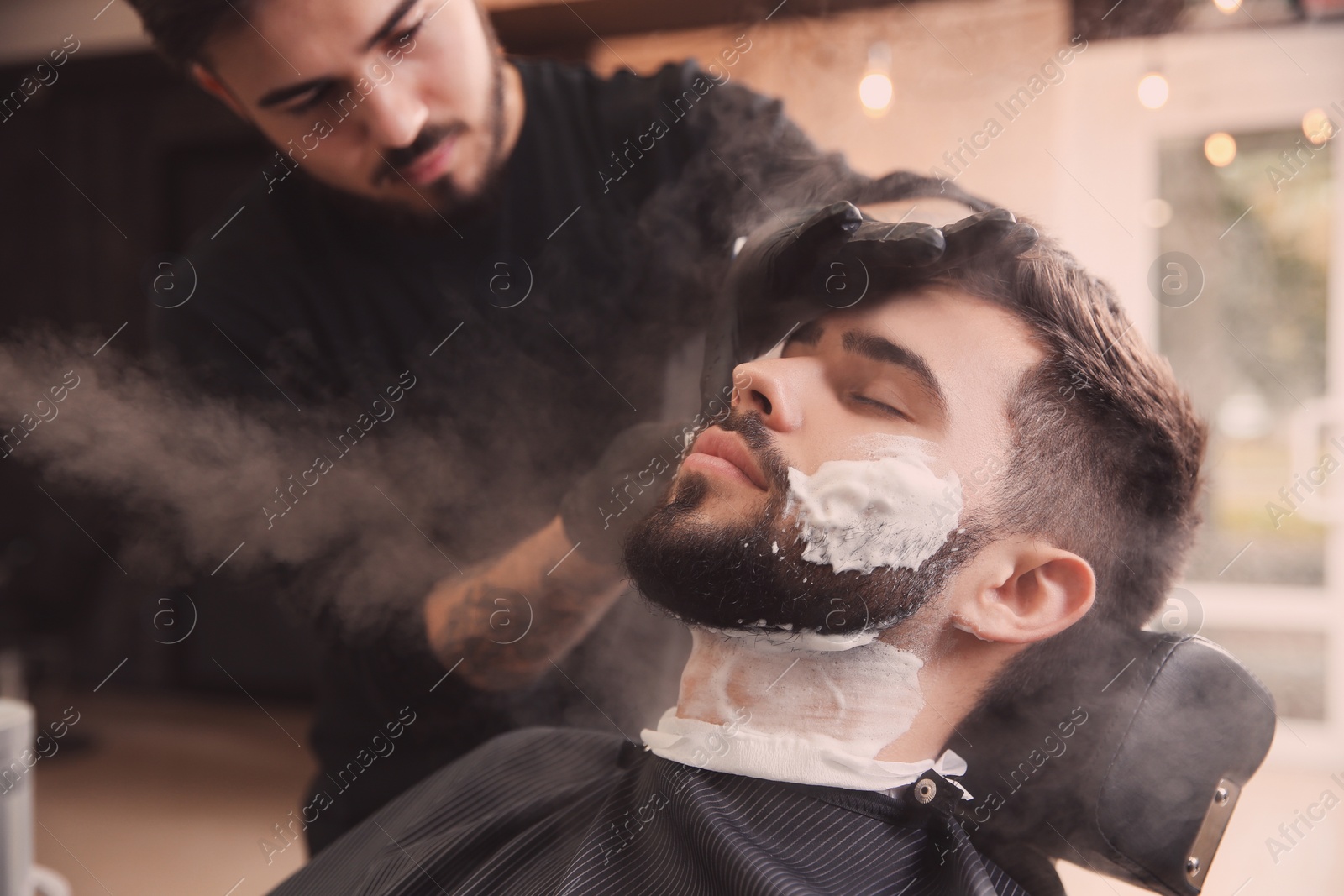 Photo of Hairdresser working with client at barbershop. Professional shaving service