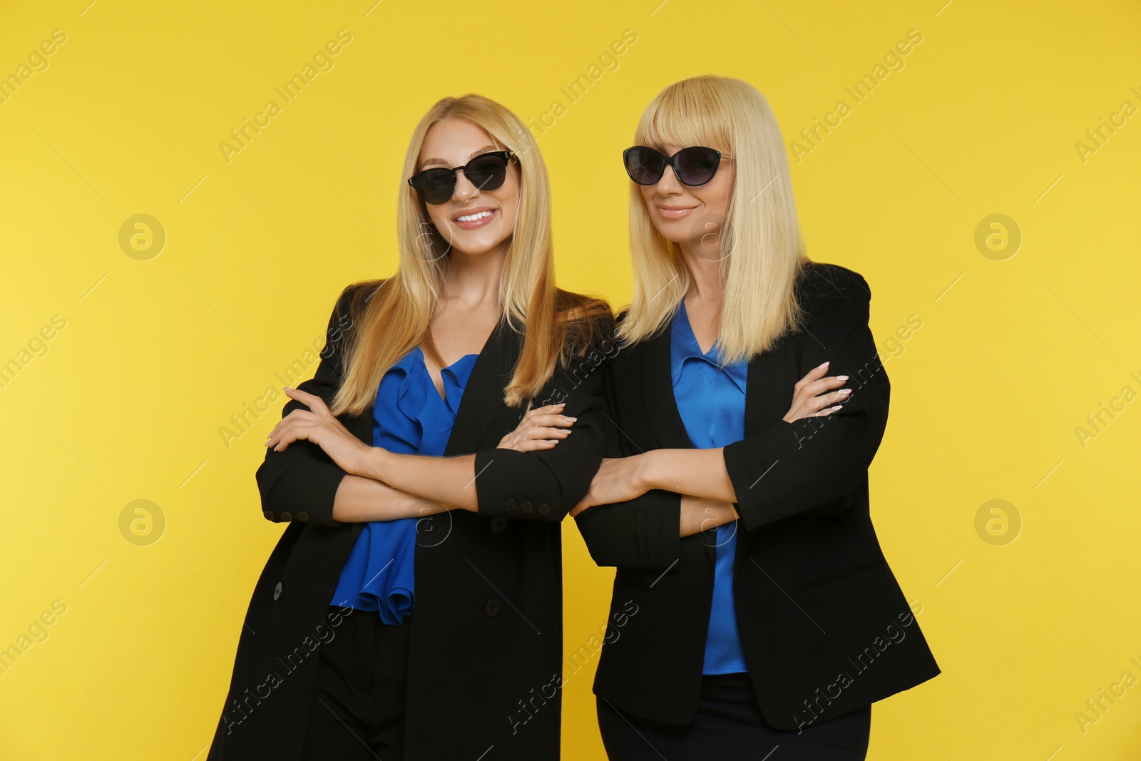 Photo of Portrait of young woman with her mature mother on yellow background