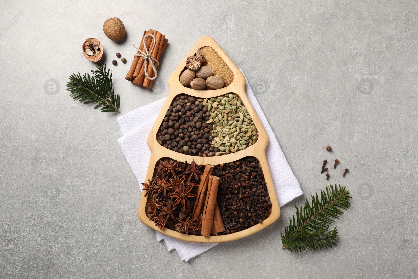 Photo of Different spices, nuts and fir branches on gray textured table, flat lay