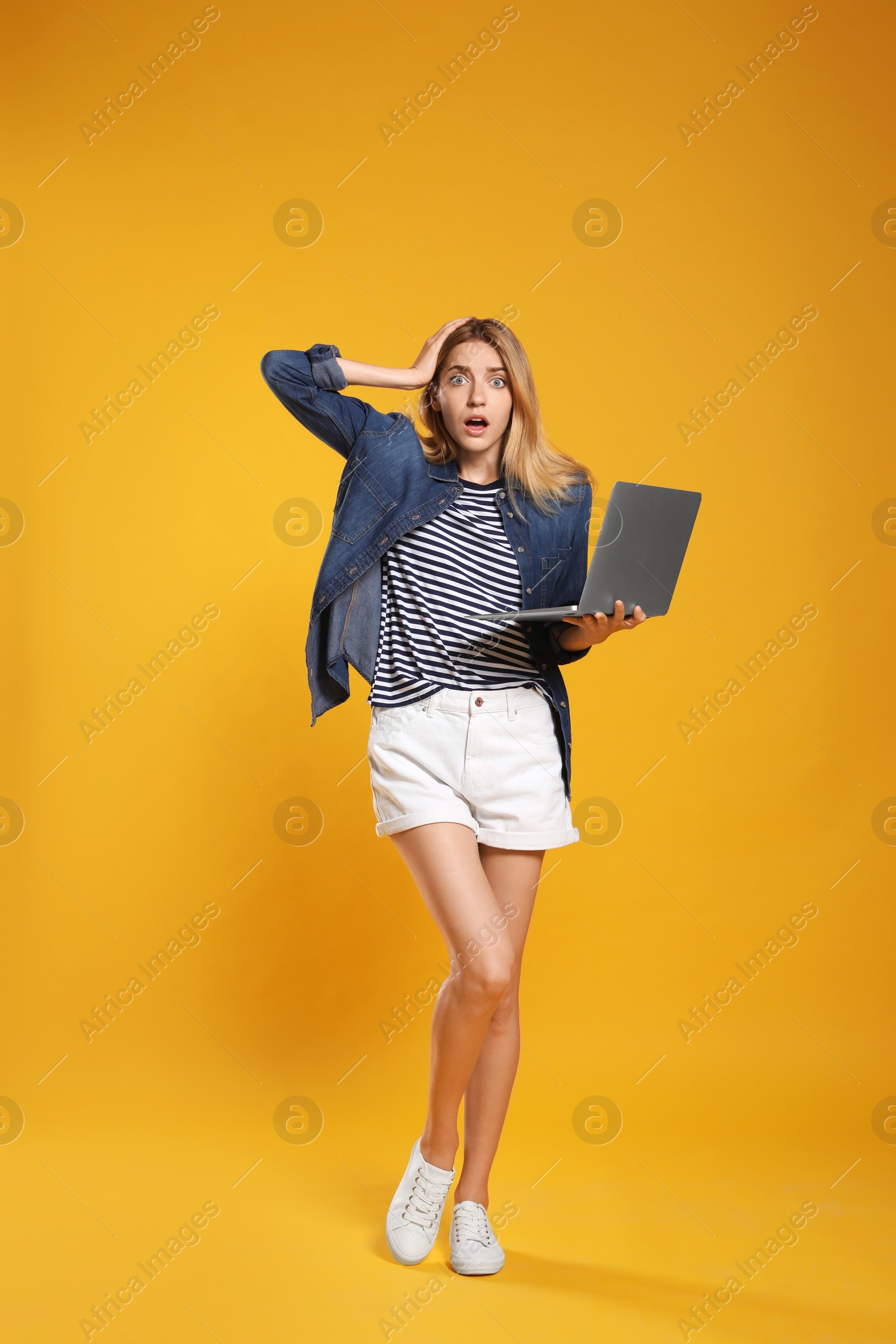 Photo of Full length portrait of emotional woman with modern laptop on yellow background