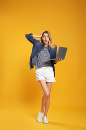 Photo of Full length portrait of emotional woman with modern laptop on yellow background