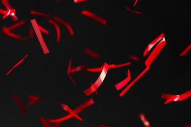 Shiny red confetti falling down on black background