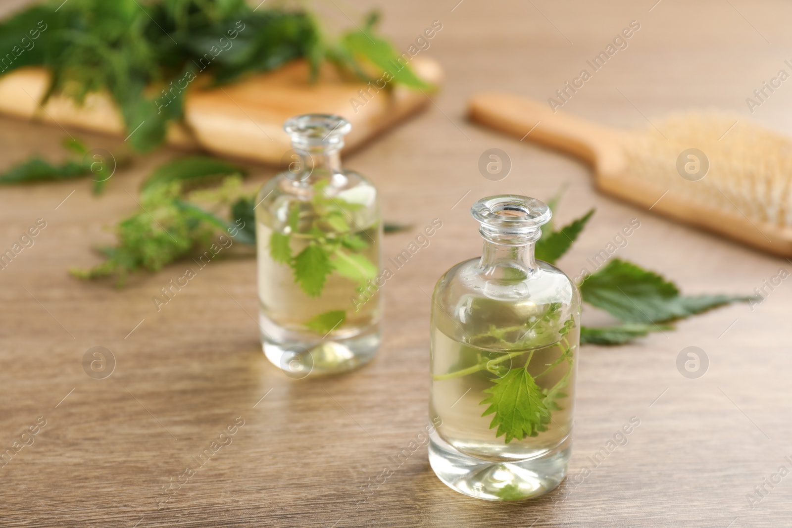 Photo of Stinging nettle extract and leaves on wooden background. Natural hair care