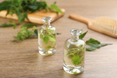 Photo of Stinging nettle extract and leaves on wooden background. Natural hair care
