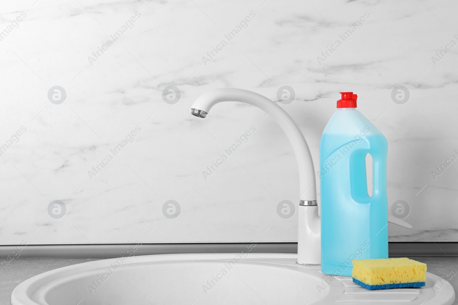 Photo of Cleaning product and sponge for dish washing near kitchen sink. Space for text