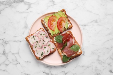 Different tasty sandwiches on white marble table, top view