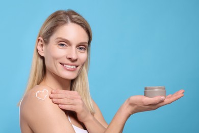 Woman with jar of body cream on light blue background