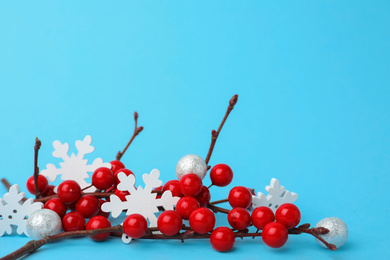 Photo of Decorative branches and snowflakes on light blue background. Winter season