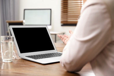 Woman using video chat on laptop in home office, closeup. Space for text