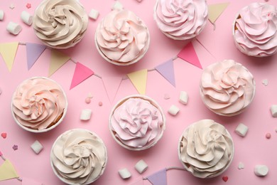 Delicious birthday cupcakes, bunting flags, marshmallows and sprinkles on pink background, flat lay