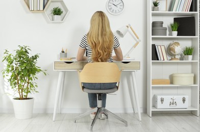 Home workplace. Woman working at comfortable desk in room, back view