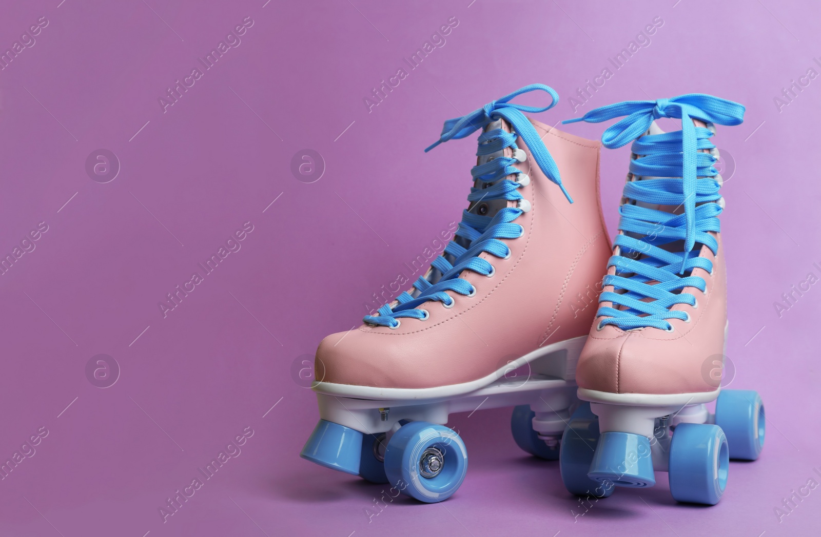 Photo of Pair of stylish quad roller skates on color background. Space for text