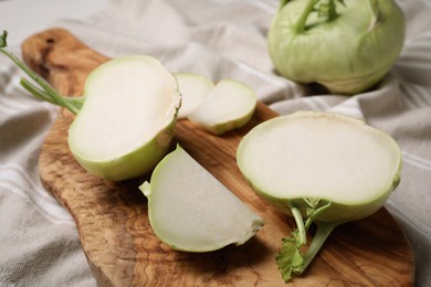 Photo of Cut kohlrabi plants on wooden board, closeup