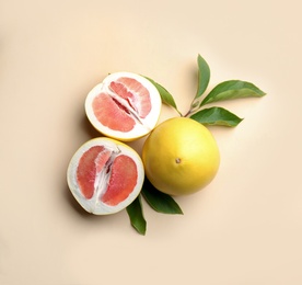 Photo of Fresh cut and whole pomelo fruits with leaves on beige background, flat lay