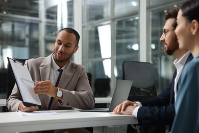 Photo of Lawyer with clipboard working with clients at table in office