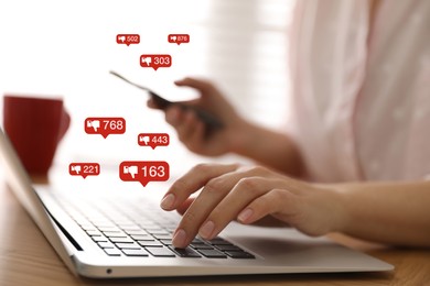 Closeup view of young woman using modern laptop with smartphone indoors and virtual dislike icons at table. Cyberbullying concept