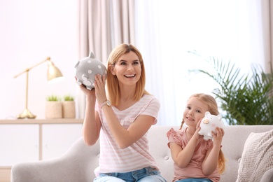 Mother and daughter with piggy banks at home