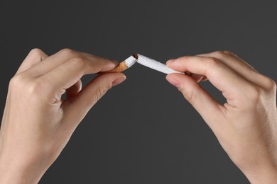 Photo of Stop smoking concept. Woman breaking cigarette on gray background, closeup