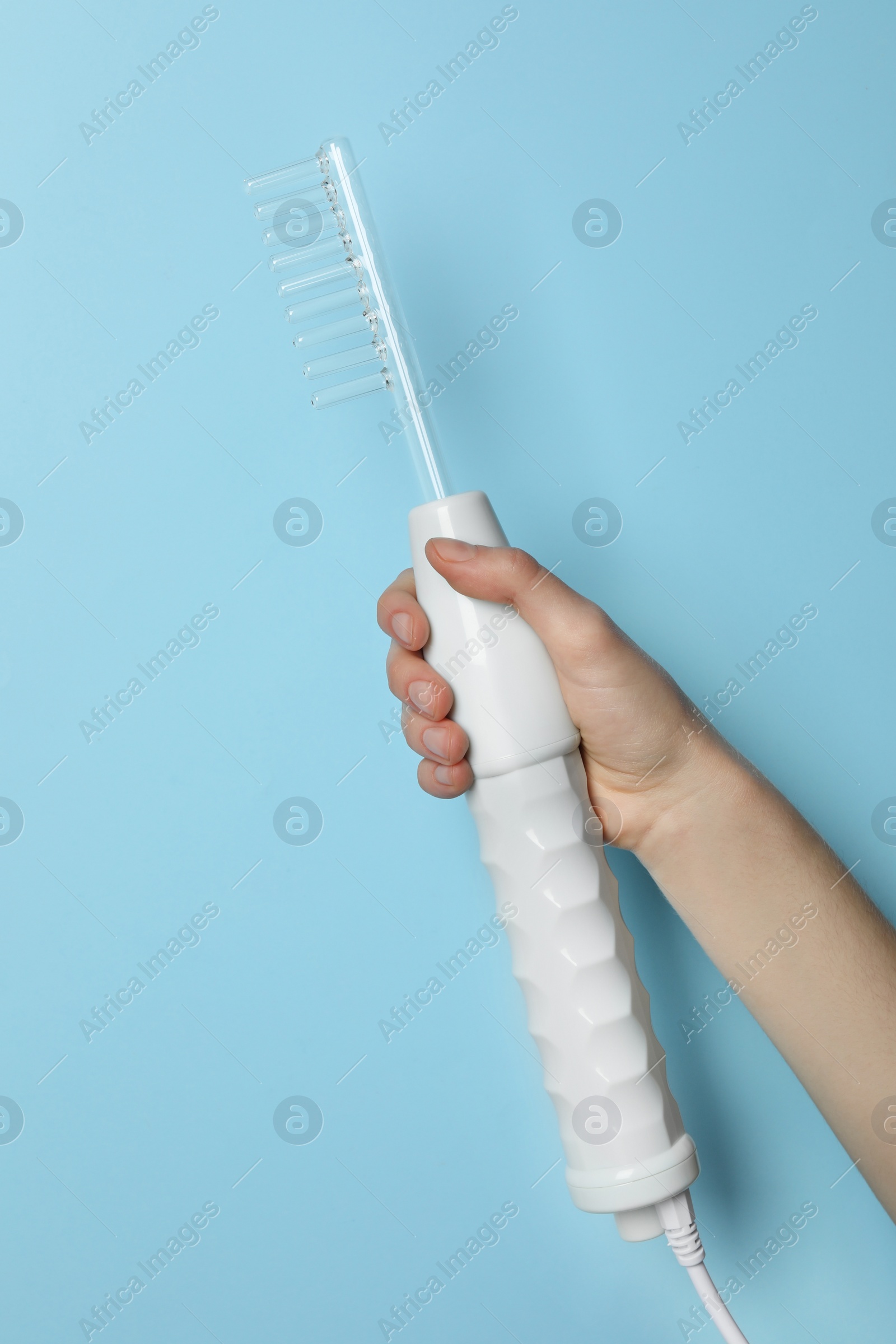 Photo of Woman with darsonval on light blue background, closeup