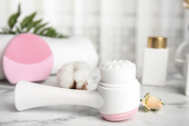 Photo of Modern face cleansing brush on marble table. Cosmetic accessory