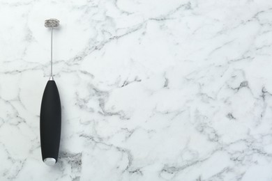 Photo of Black milk frother wand on white marble table, top view. Space for text