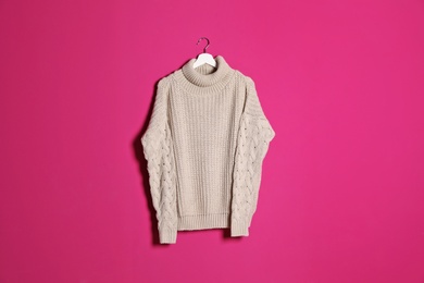 Hanger with stylish sweater on color background