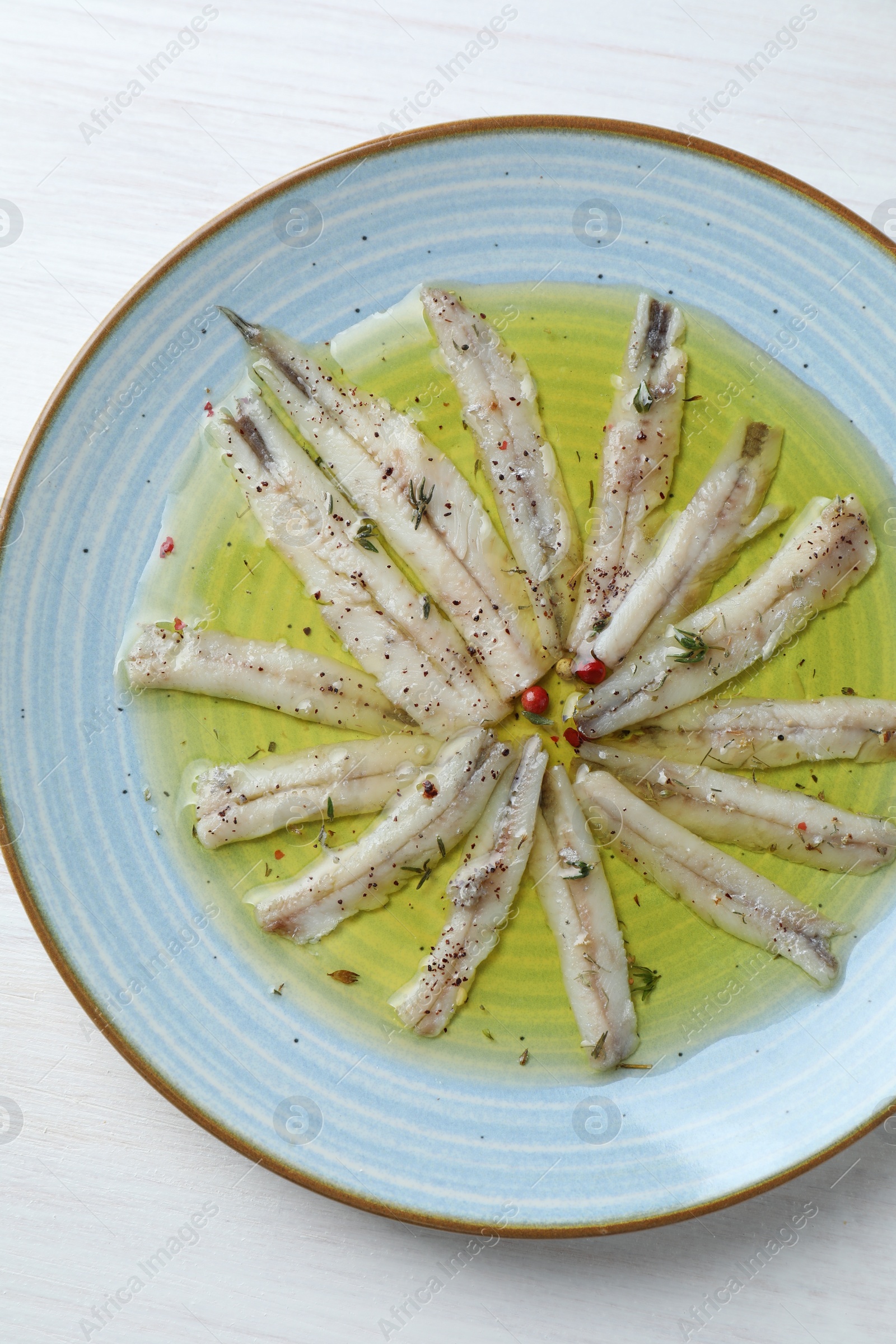 Photo of Tasty pickled anchovies with spices on white table, top view