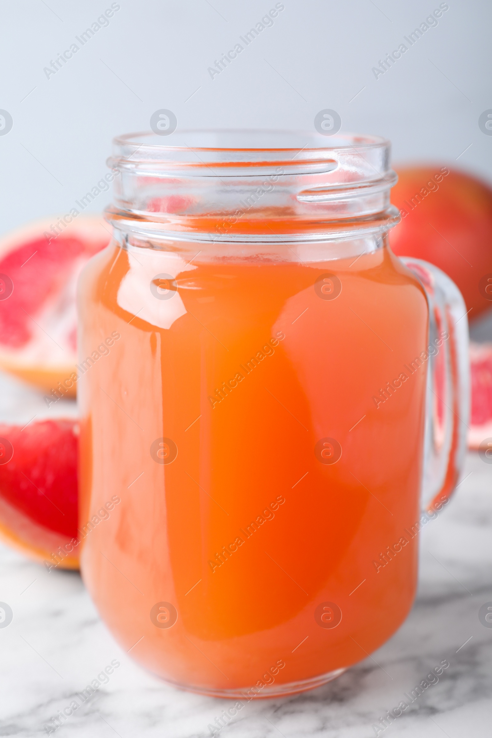 Photo of Tasty freshly made grapefruit juice on white marble table