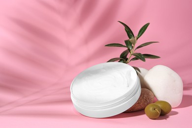 Jar of natural cream, stones and olives on pink background. Cosmetic products