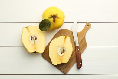 Tasty ripe quince fruits and knife on white wooden table, flat lay