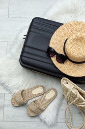 Photo of Suitcase packed for trip and summer accessories on floor, flat lay