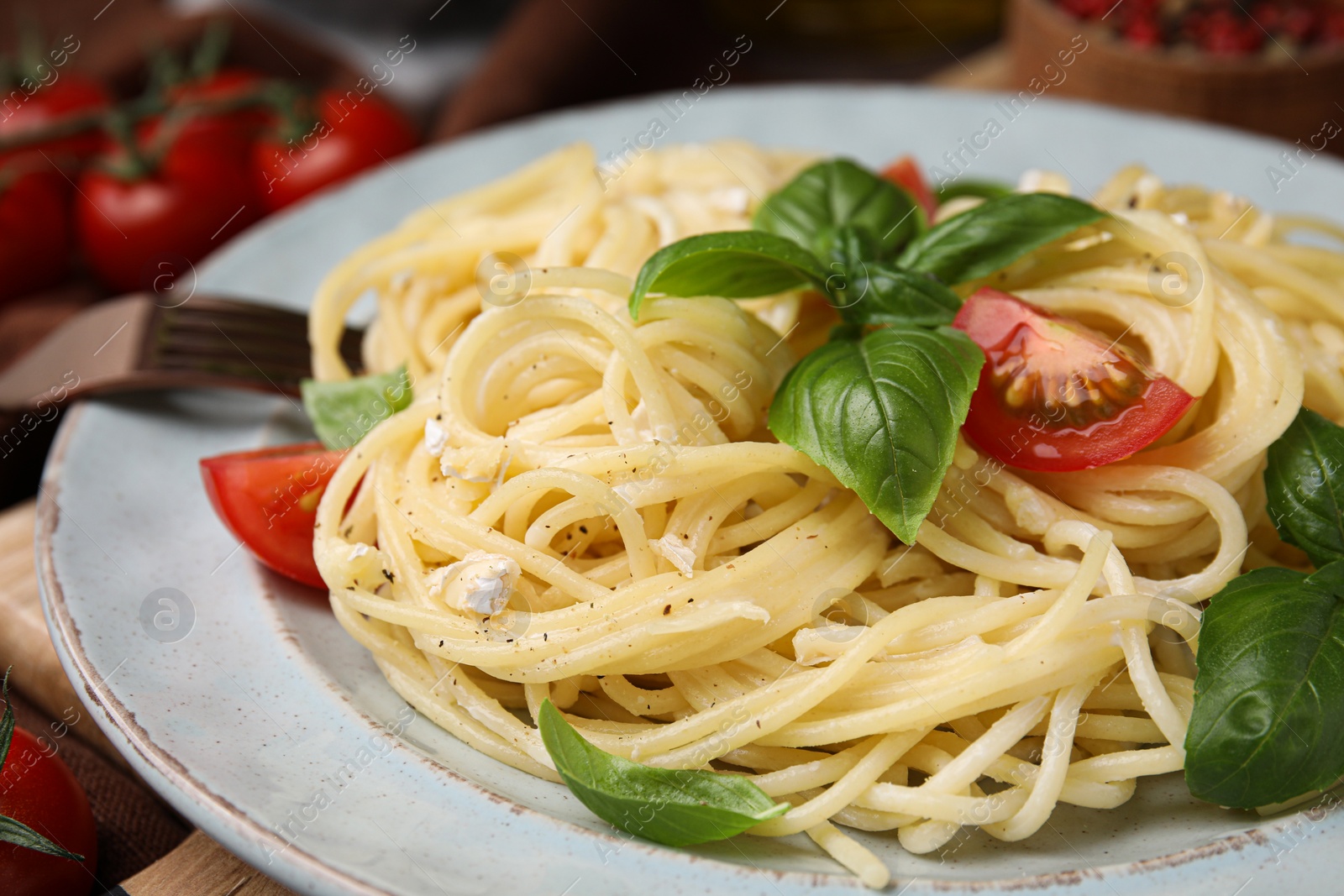 Photo of Delicious pasta with brie cheese, tomatoes and basil leaves on table, closeup