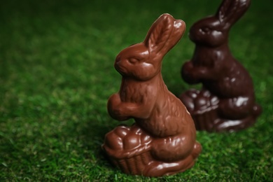 Photo of Chocolate bunnies on green grass, space for text. Easter celebration