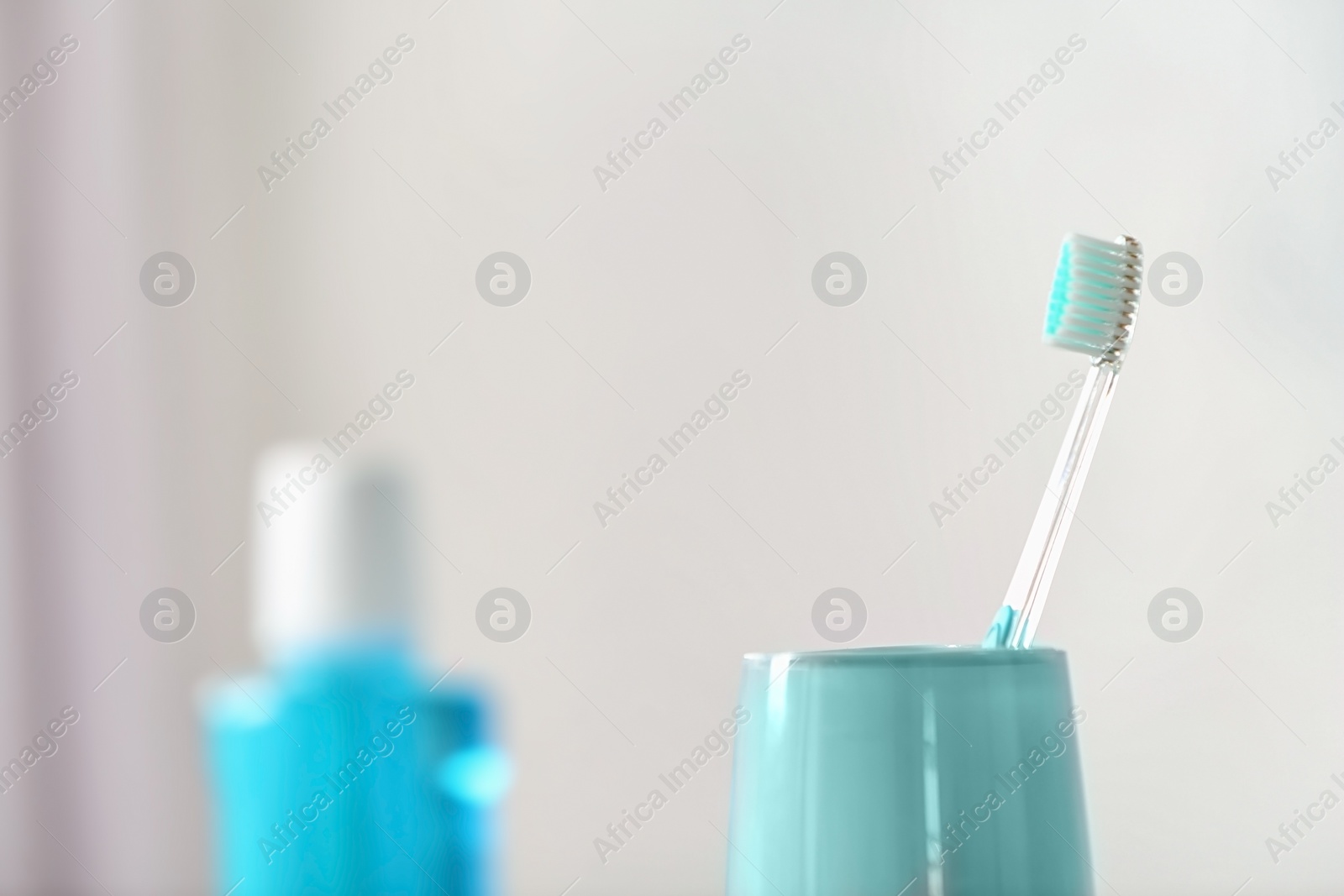 Photo of Cup with toothbrush against blurred background. Dental care