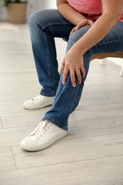 Mature woman suffering from leg pain at home, closeup