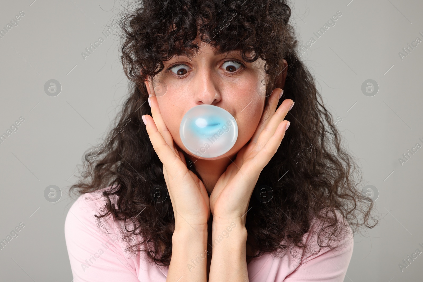 Photo of Beautiful young woman blowing bubble gum on grey background