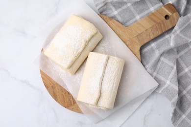 Photo of Raw puff pastry dough on white marble table, top view